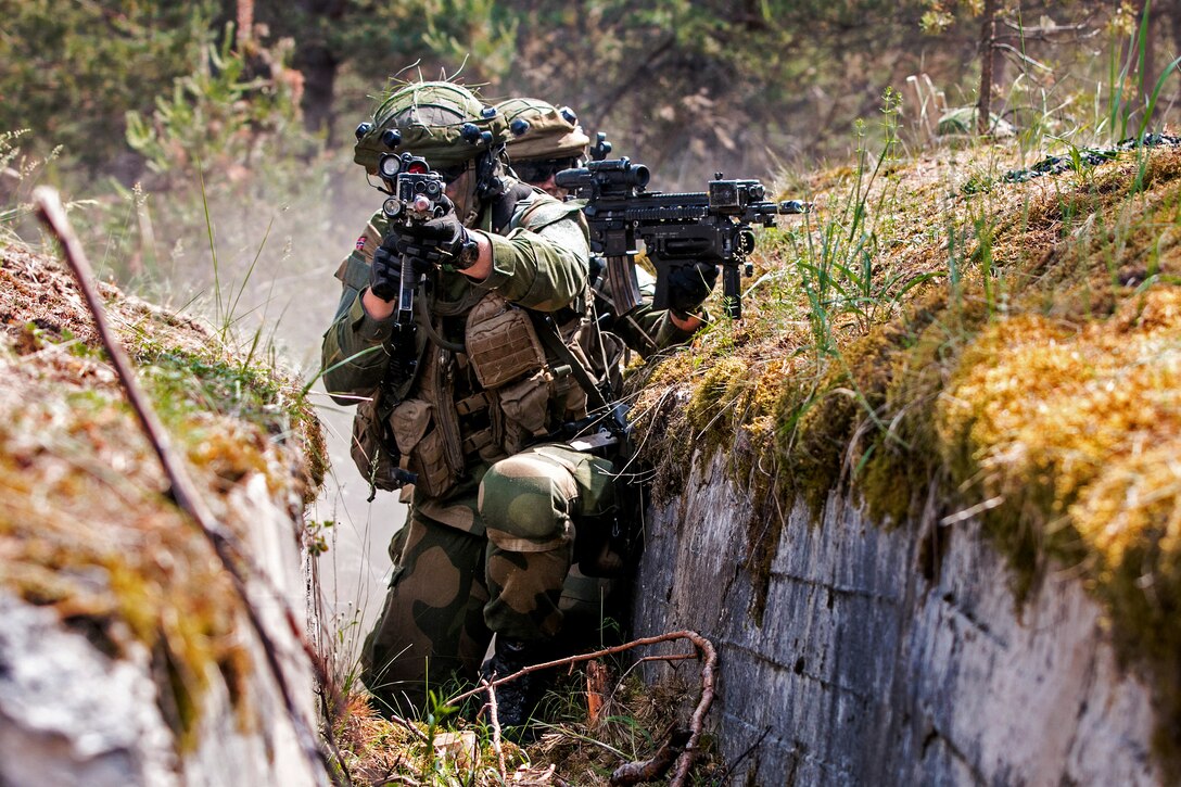Norwegian soldiers advance down a trench controlled by opposing forces.