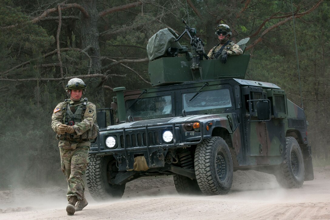 A U.S. soldier ground guides a Humvee to an assembly area.