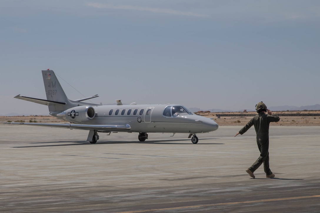 Lance Cpl. Matthew Nelson, a helicopter crew chief with Marine Light Helicopter Attack Squadron 775, directs the taxi of a UC-35 Citation with distinguished visitors landing at Camp Wilson during Integrated Training Exercise 4-18 at Marine Corps Air Ground Combat Center Twentynine Palms, Calif., June 13, 2018.