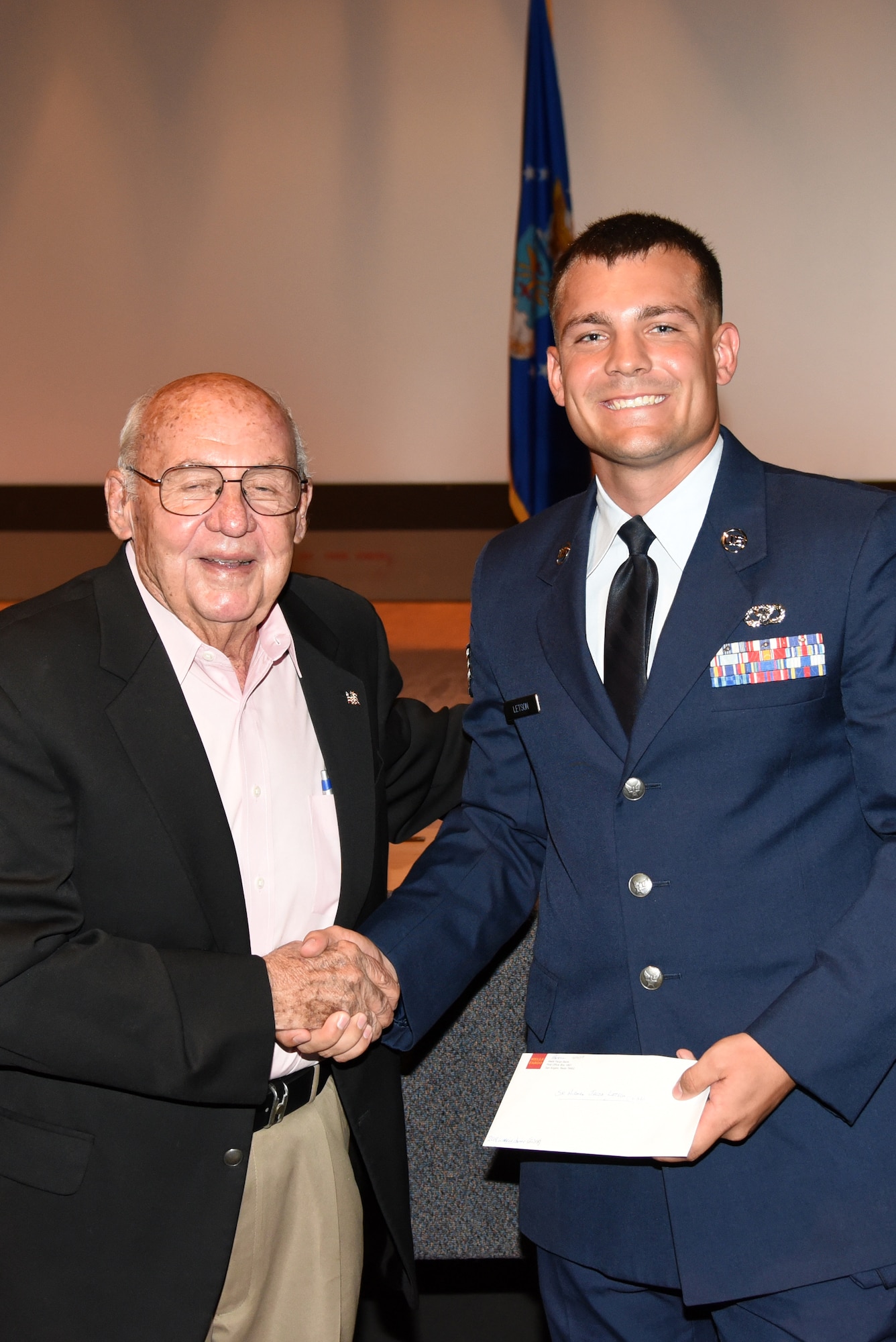 Retired U.S. Air Force Col. Charles Powell, former 17th Training Wing commander, hands Senior Airman Jacob Letson, 17th Civil Engineer Squadron engineering technician, the Powell Warrior Award during a Community College of the Air Force graduate ceremony at the base theater on Goodfellow Air Force Base, Texas, June 15, 2018. The award is given to CCAF graduates who have displayed the highest degree of professional military excellence. (U.S. Air Force photo by Staff Sgt. Joshua Edwards/Released)