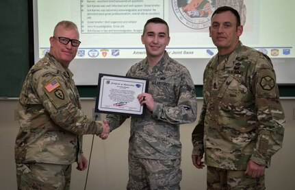U.S. Army Col. Adam Lange, 673d Air Base Wing and Joint Base Elmendorf-Richardson vice-commander, and U.S. Army Sgt. Maj. Jerry Byrd, Garrison Sgt. Maj. for 673d Air Base Wing, present a certificate of recognition to Senior Airman Lucas Karnes, 673d Comptroller Squadron financial services technician, at JBER, Alaska, June 15, 2018. The certificate recognizes Karnes as the JBER monthly customer service individual for exceptional customer service for the month of June.