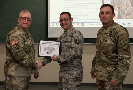 U.S. Army Col. Adam Lange, 673d Air Base Wing and Joint Base Elmendorf-Richardson vice-commander, and U.S. Army Sgt. Maj. Jerry Byrd, Garrison Sgt. Maj. for 673d Air Base Wing, present a certificate of recognition to a member of the JBER Hospital Laboratory, at JBER, Alaska, June 15, 2018. The certificate recognizes the team for exceptional customer service.