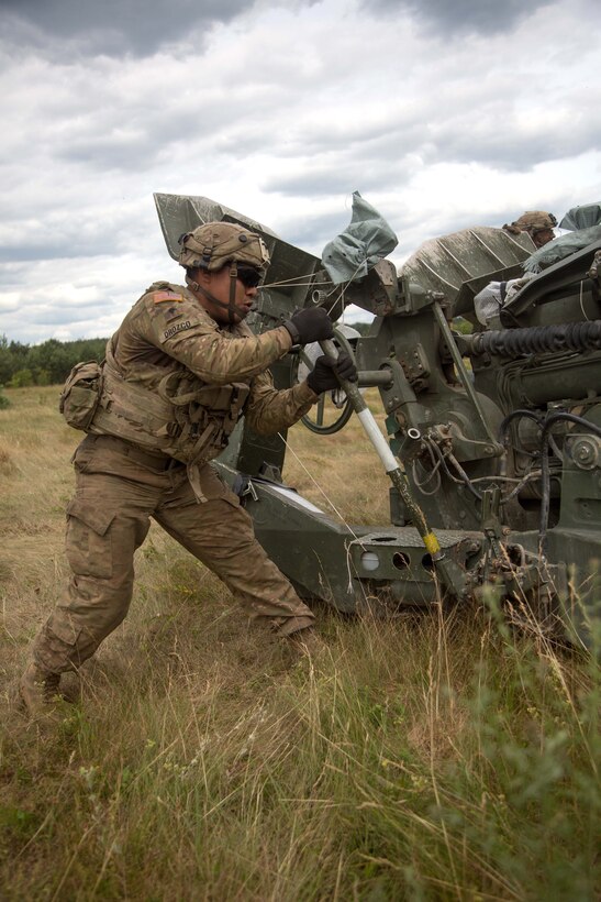 A soldier pumps a handle to raise an M777A2 155mm howitzer before being towed.