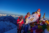 Matt Moniz, Mike Moniz, and guide pose for a photo on the summit of Mount Everest
with a U.S. 7th Fleet flag.  Photo courtesy of the Moniz family.