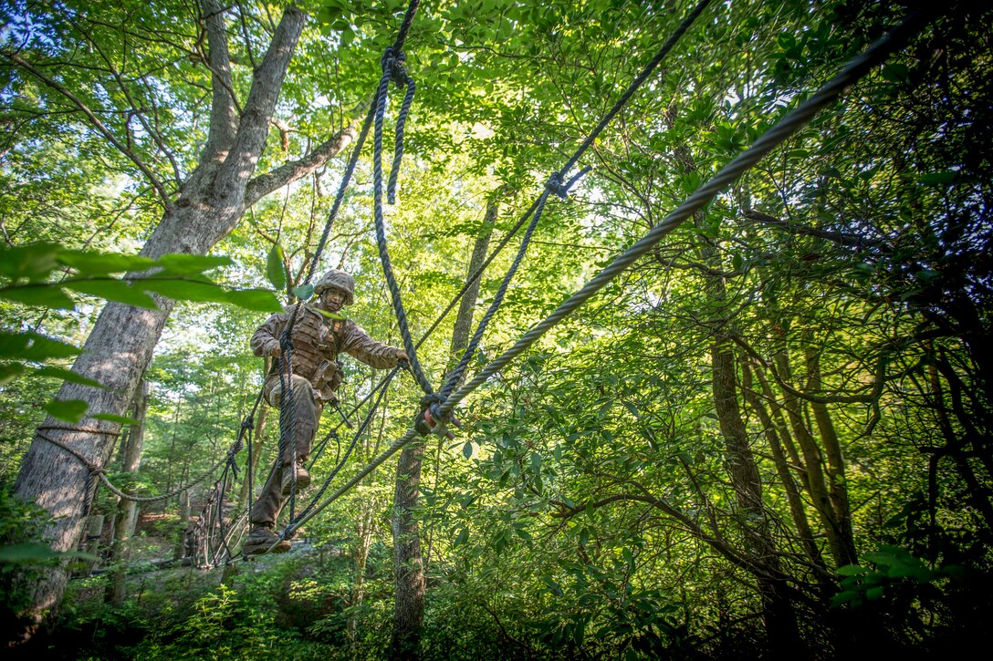 A Marine crosses a rope bridge.