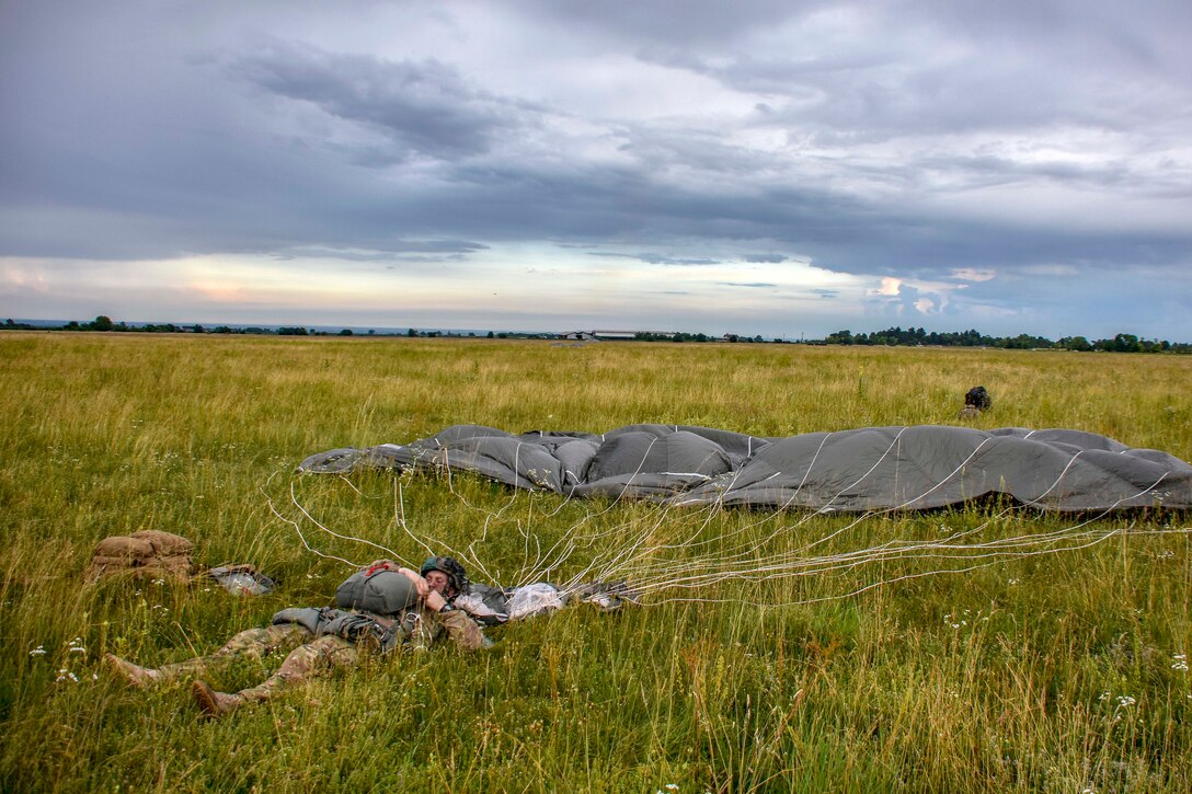 A soldier recovers his chute and gear after conducting airborne operation.