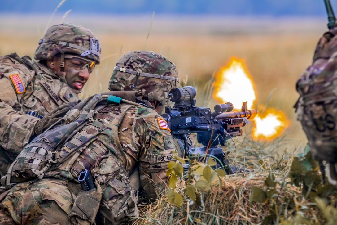 Soldiers lay on the ground and fire a weapon.