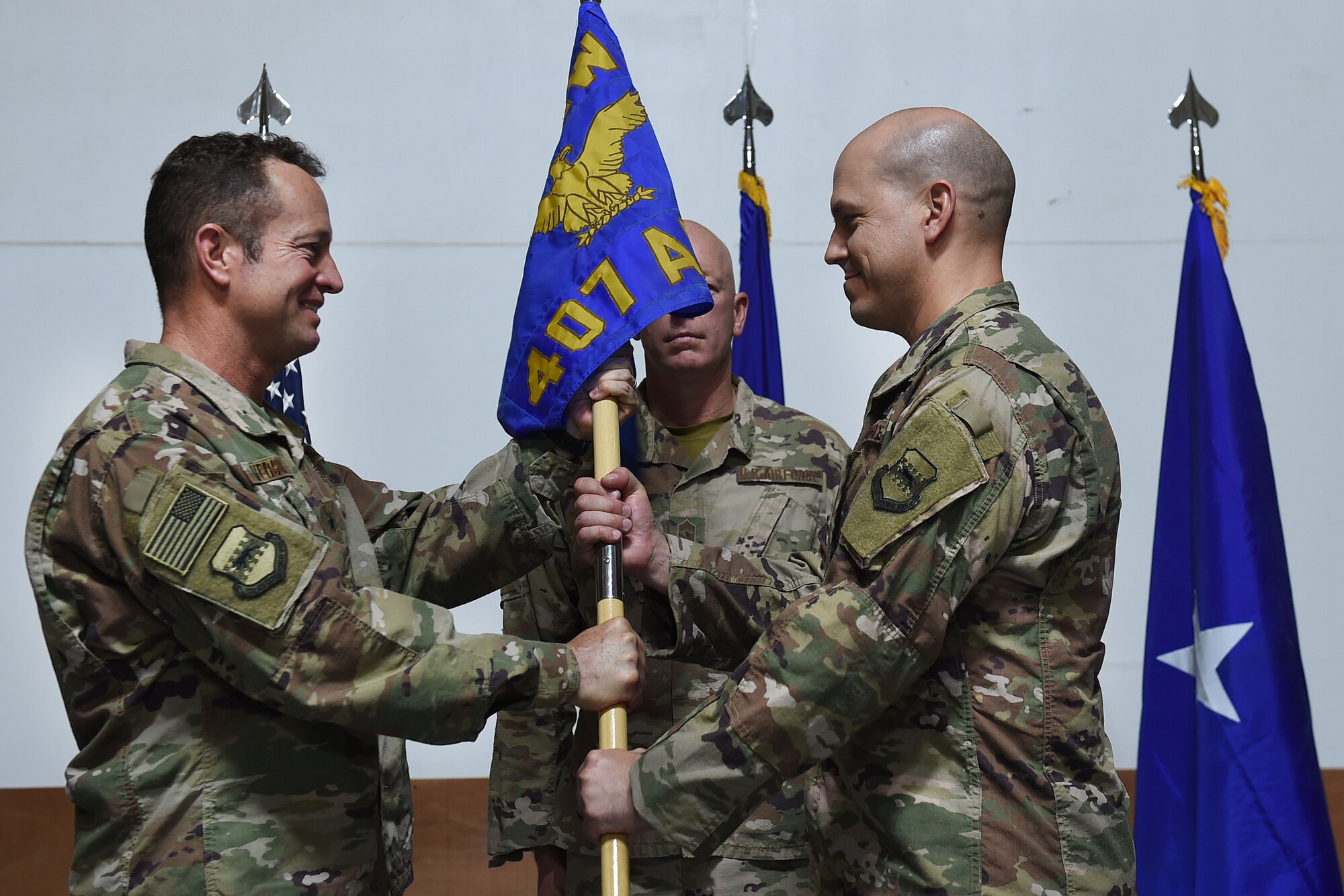 two airmen pass a guidon to each other