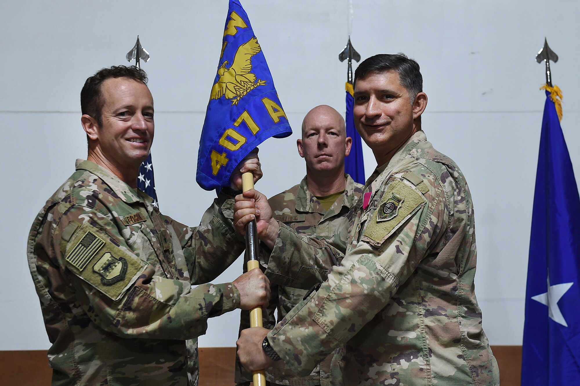 two airmen pose for a photo holding a guidon