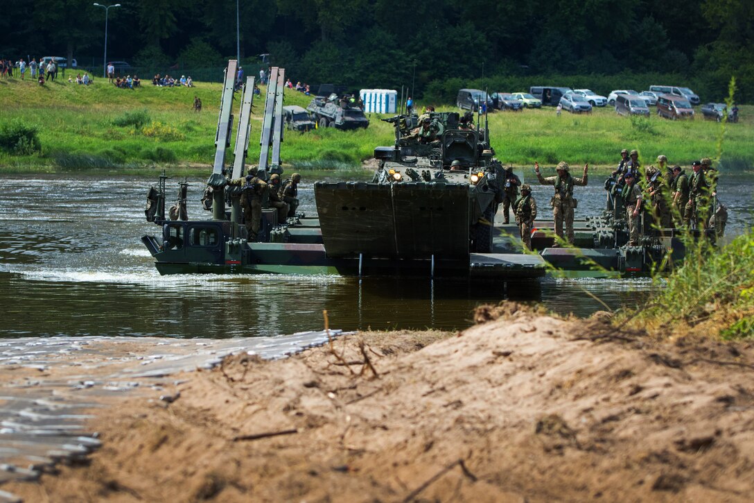 German and British soldiers use several M3 Amphibious Rig Bridges to ferry elements of the 2nd Cavalry Regiment and their soldiers across the Nemen River.