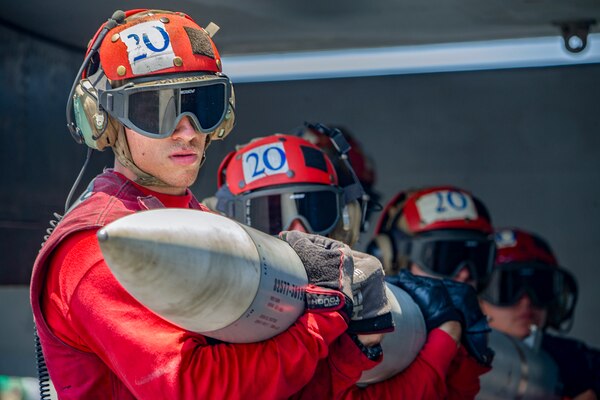 Four sailors carry ordnance.