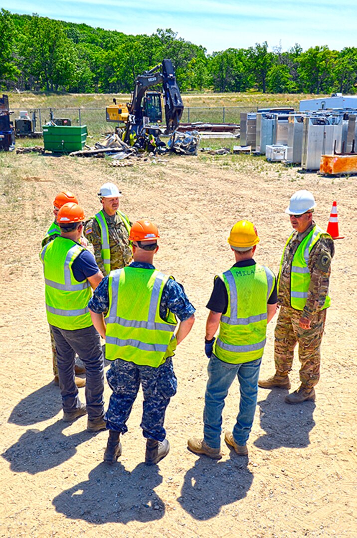 Camp Grayling Joint Maneuver Training Center Garrison Commander Army Col. Ed Hallenbeck and Command Sgt. Maj. John Engel are briefed on DLA Disposition Services capabilities and watch as forklifts and industrial refrigerators are turned to scrap during a DLA expeditionary exercise at their base in June.