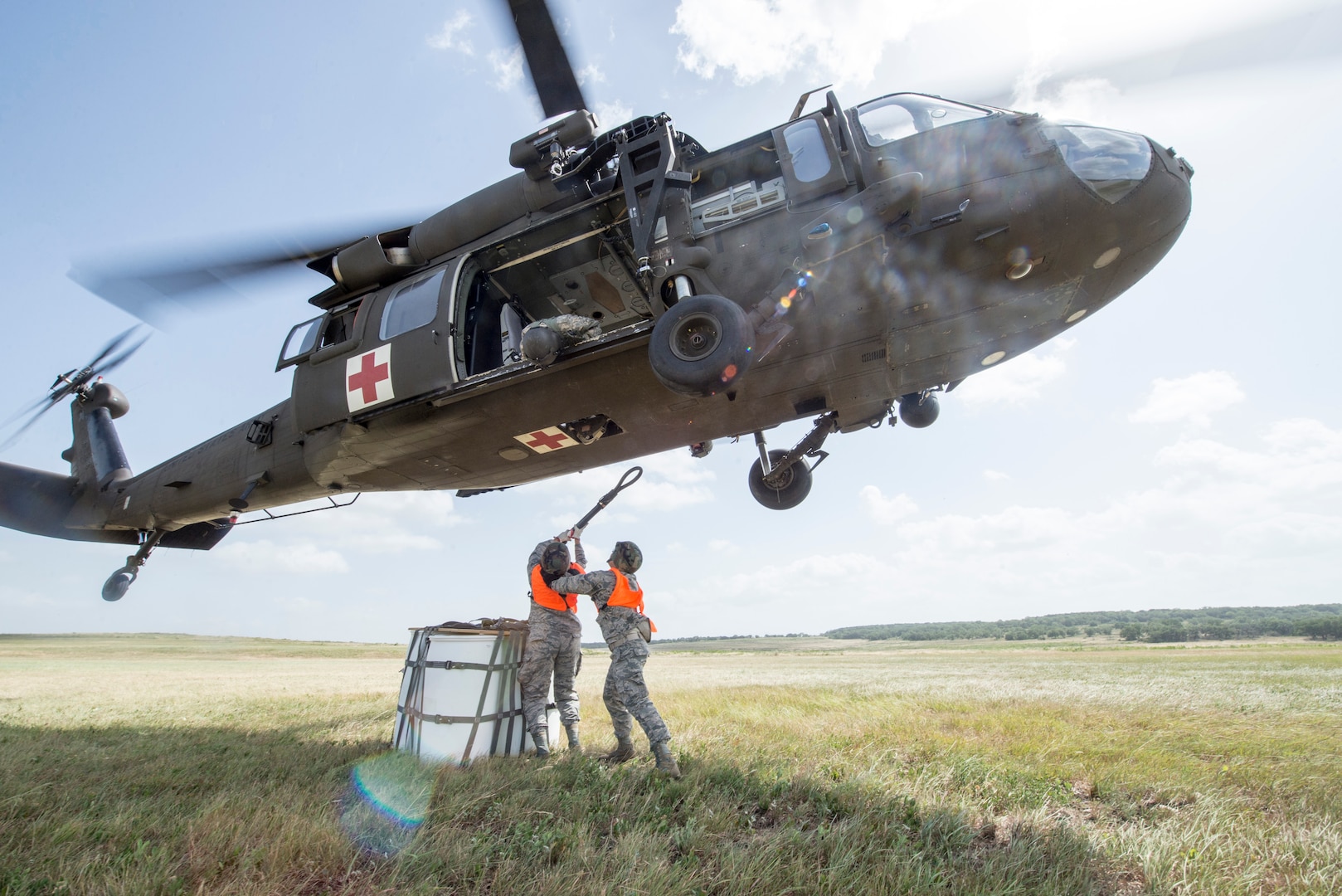 Airman 1st Class Alicia Deluna and Air Force Staff Sgt. John Tapia 74th Aerial Port Squadron aerial transportation technicians, attach a 2,000 pound sling load to a UH-60 Black Hawk helicopter during Operation Lone Star Vigilance June 10, 2018, at Joint Base San Antonio-Camp Bullis, Texas. Operation Lone Star Vigilance was a joint-training exercise involving Active-Duty and Reserve Airmen and Soldiers from the Texas Army National Guard from installations across San Antonio. The multi-service missions saw the successful completion of aerial reconnaissance, sling loading of cargo, MEDEVAC hoists, personnel recovery and the simultaneous operation of multiple helicopter landing zones. (U.S. Air Force photo by Senior Airman Stormy Archer)