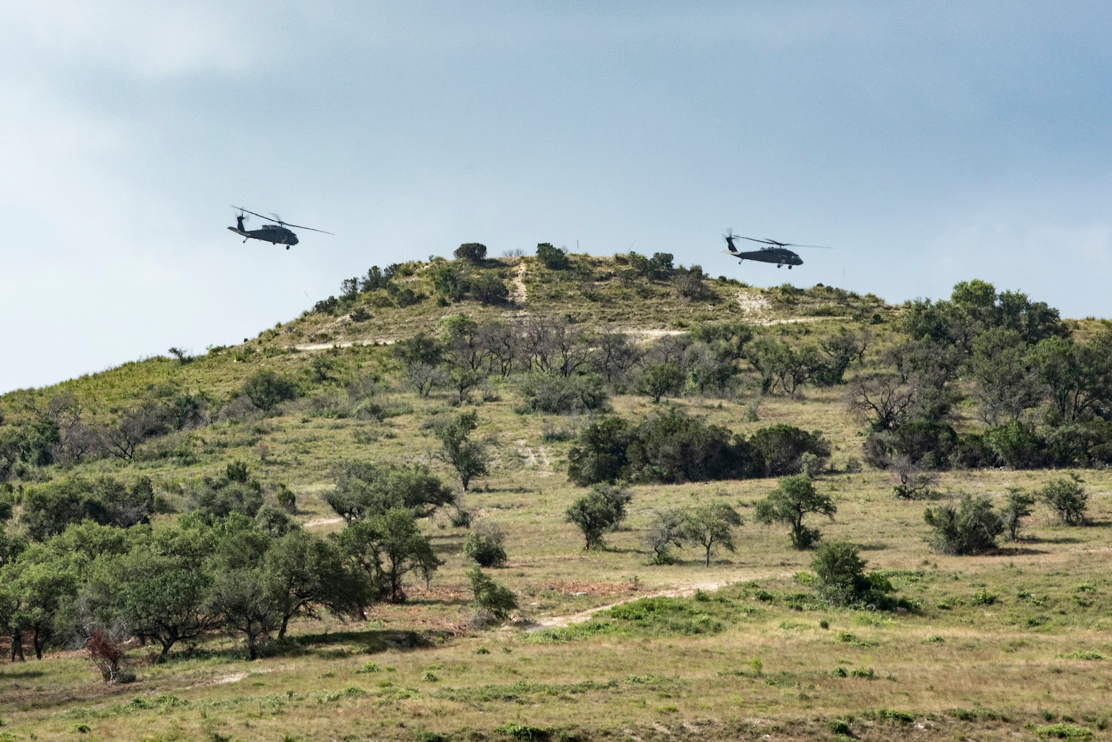 Soldiers from Texas Army National Guard Company C, 2-149 Aviation, fly across Butte Hill in preparation for a hoist mission as part of Operation Lone Star Vigilance June 10, 2018, at Joint Base San Antonio-Camp Bullis, Texas. Operation Lone Star Vigilance was a joint-training exercise involving Active-Duty and Reserve Airmen and Soldiers from the Texas Army National Guard from installations across San Antonio. The multi-service missions saw the successful completion of aerial reconnaissance, sling loading of cargo, MEDEVAC hoists, personnel recovery and the simultaneous operation of multiple helicopter landing zones. (U.S. Air Force photo by Senior Airman Stormy Archer)