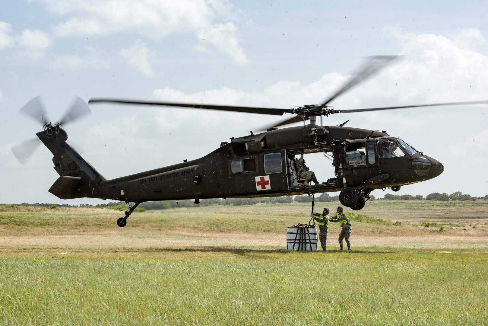 Airmen from the 433rd Airlift wing attach a 2,000 pound sling load to a UH-60 Black Hawk helicopter during Operation Lone Star Vigilance June 10, 2018, at Joint Base San Antonio-Camp Bullis, Texas. Operation Lone Star Vigilance was a joint-training exercise involving Active-Duty and Reserve Airmen and Soldiers from the Texas Army National Guard from installations across San Antonio. The multi-service missions saw the successful completion of aerial reconnaissance, sling loading of cargo, MEDEVAC hoists, personnel recovery and the simultaneous operation of multiple helicopter landing zones. (U.S. Air Force photo by Senior Airman Stormy Archer)