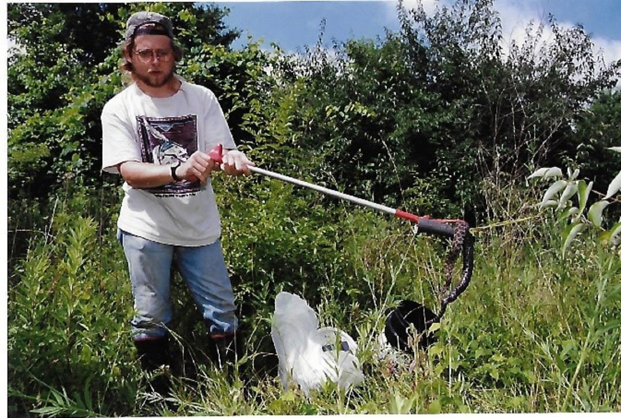 Greg Colwell, a former base biologist here, is wrangling a Massasauga snake on base as part of a survey from an area on base known as the War Fighter Training Center. (Courtesy photo)
