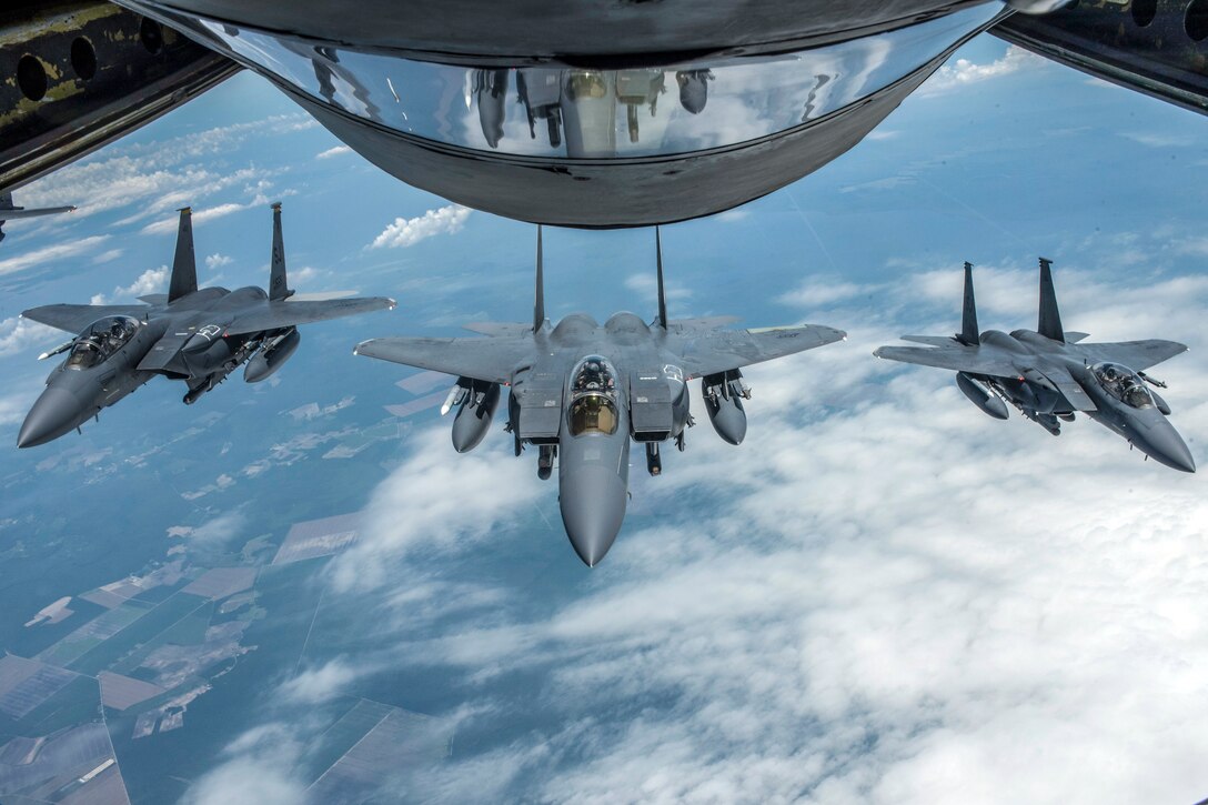 Three aircraft fly behind a larger aircraft.