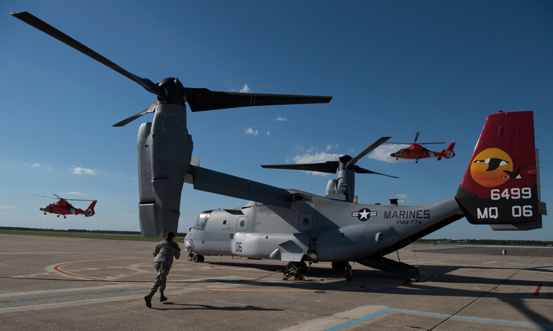 Two U.S. Coast Guard Air Station Atlantic City HH-65 Dolphin fly over a Marine Medium Tilt Roader Squadron (VMM) 774 V-22 Osprey before refueling on Coast Guard Air Station Atlantic City, N.J., June 14, 2018. The Marines and Coast Guardsmen conducted the first forward air-refueling point between the two helicopters during the 2018 Marine Aircraft Group 49 Combined Arms Exercise. (U.S. Air Force photo by Airman Ariel Owings)