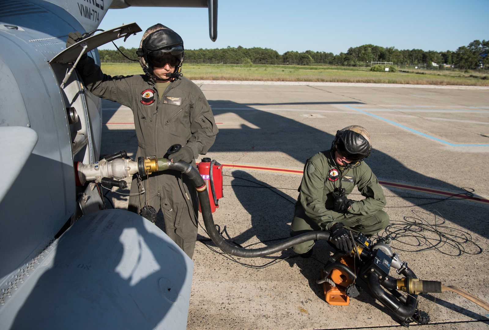 U.S. Marine Corps Staff Sgt. Ken Dorswitt and Sgt. Christopher Stewart, Marine Medium Tilt Roader Squadron (VMM) 774 crew chiefs, set-up a refueling line during a forward air-refueling point on Coast Guard Air Station Atlantic City, N.J., June 14, 2018. The fueling line drew fuel from a VMM-774 V-22 Osprey to a U.S. Coast Guard Air Station Atlantic City HH-65 Dolphin and was the first time the forward air-refueling point was performed. (U.S. Air Force photo by Airman Ariel Owings)