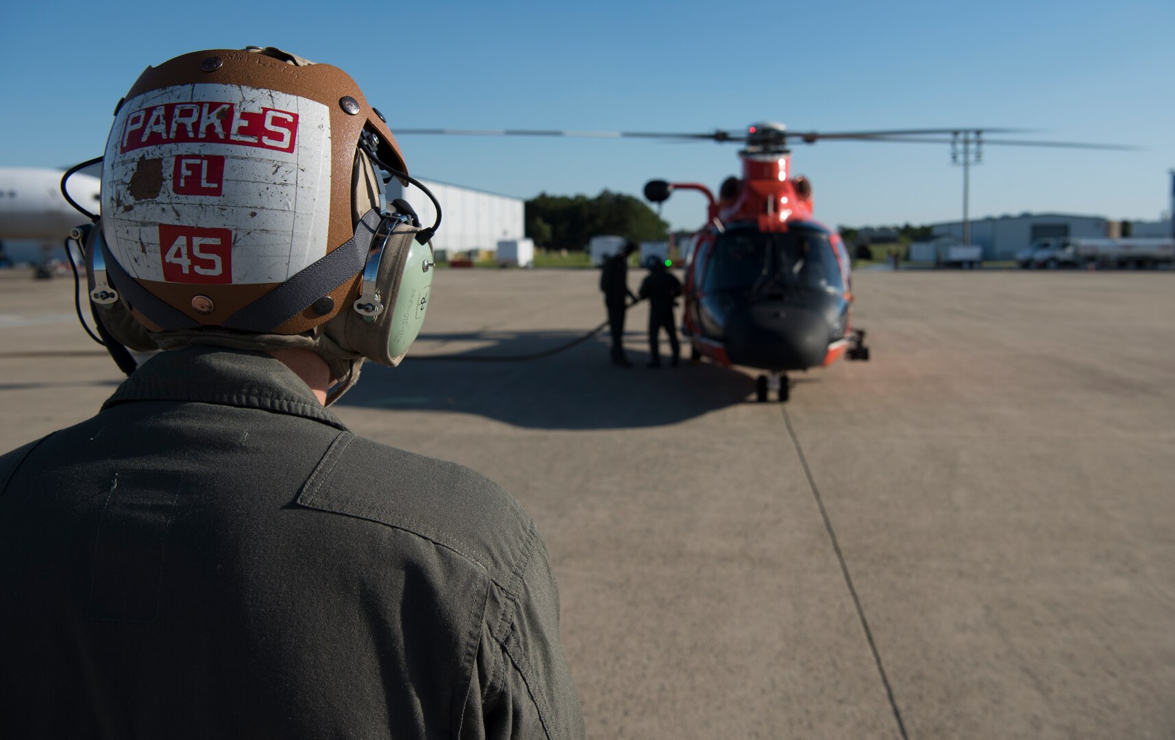 U.S. Marine Corps Sgt. Robert Parkes, Marine Medium Tilt Roader Squadron (VMM) 774 V-22 crew chief, poses in front of a U.S. Coast Guard Air Station Atlantic City HH-65 Dolphin on Coast Guard Air Station Atlantic City, N.J., June 14, 2018. The Marines conducted a forward air-refueling point for the first time – refueling an HH-65 with a VMM-774 V-22 Osprey. (U.S. Air Force photo by Airman Ariel Owings)