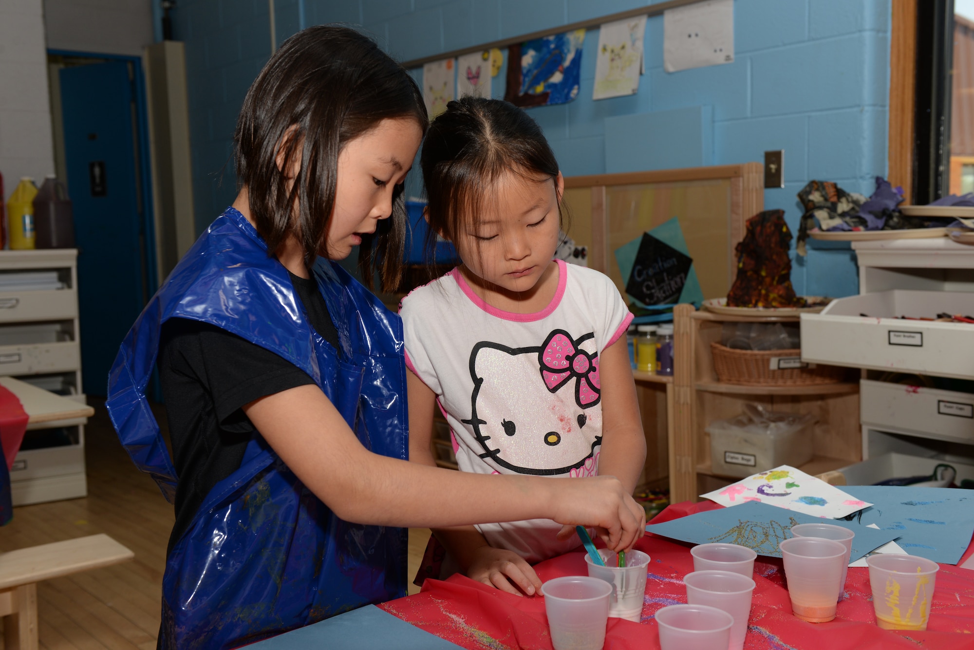 Two children paint pictures at the Youth Center on Ellsworth Air Force Base, S.D., June 13, 2018. The open recreation program during the summer consists of weekly field trips off base, family bonding events and weeklong specialty camps specializing in theater or music, where students can practice their talents in a professional recording studio. (U.S. Air Force photo by Airman 1st Class Nicolas Z. Erwin)