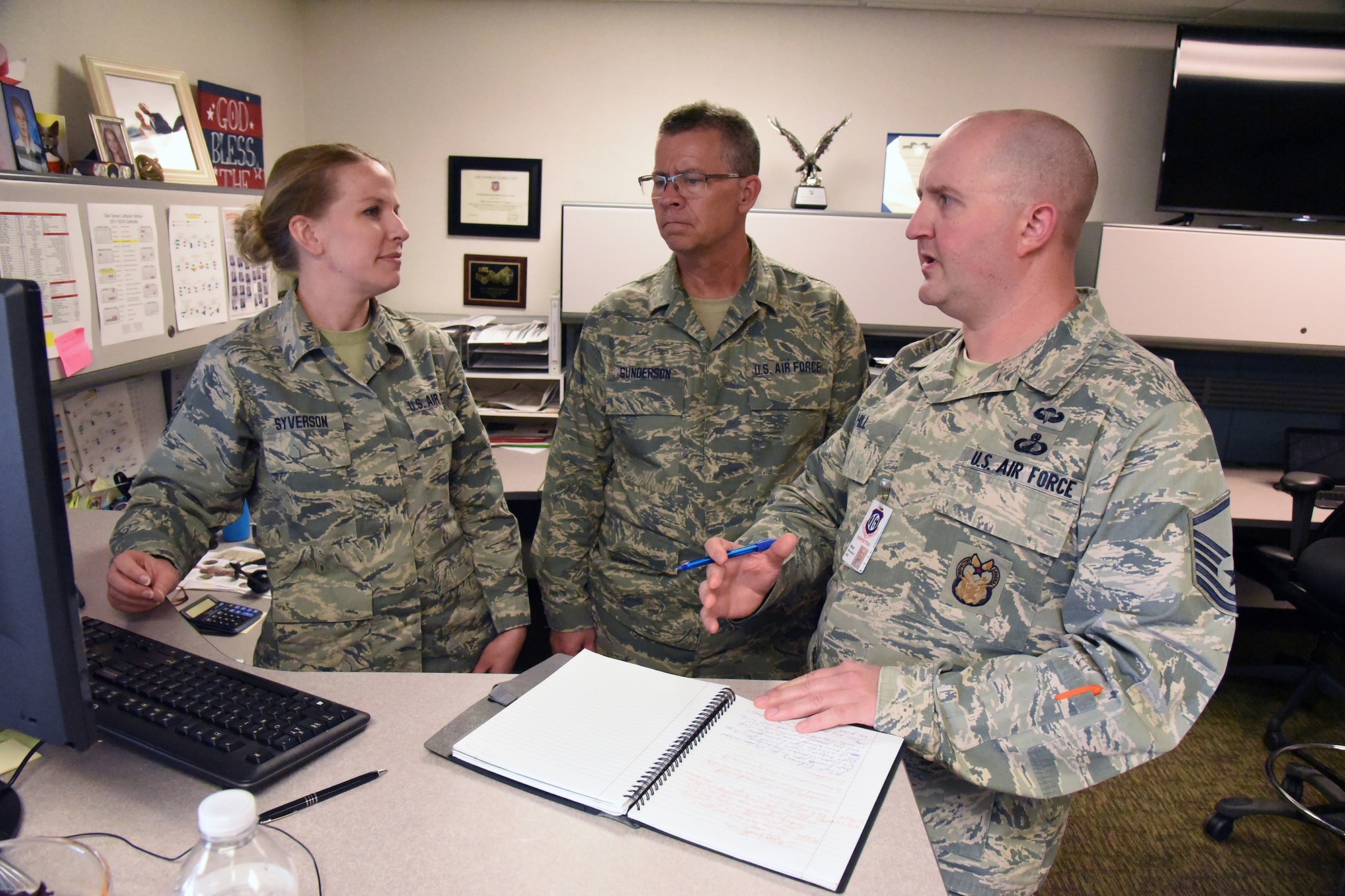 Master Sgt. Brandon Hill, of the Air Combat Command (ACC) inspector general team, right, discusses unit standards and practices with Tech. Sgt. Rachel Syverson, left, and Senior Master Sgt. Lee Gunderson, both assigned to the 119th Logistics Readiness Squadron contracting office, during a unit effectiveness inspection (UEI) at the North Dakota Air National Guard Base, Fargo, N.D., May 19, 2018.