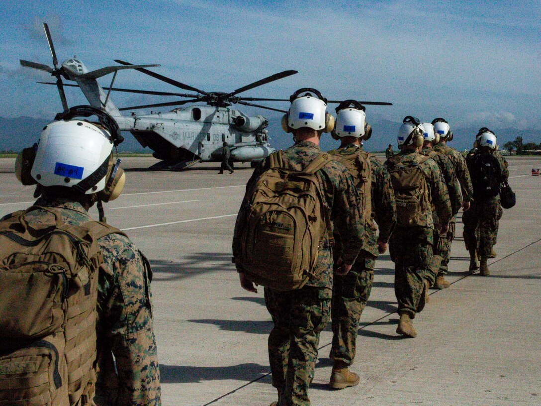 Marines march in line at an airfield.