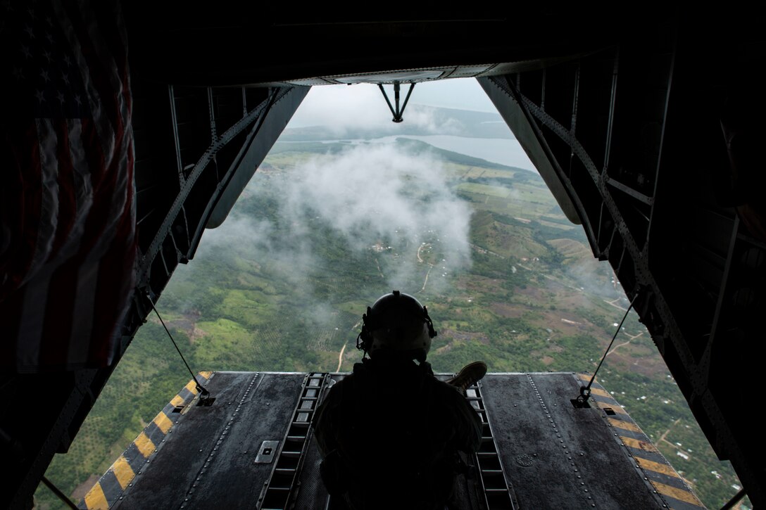A Marine looks out the back of a helicopter