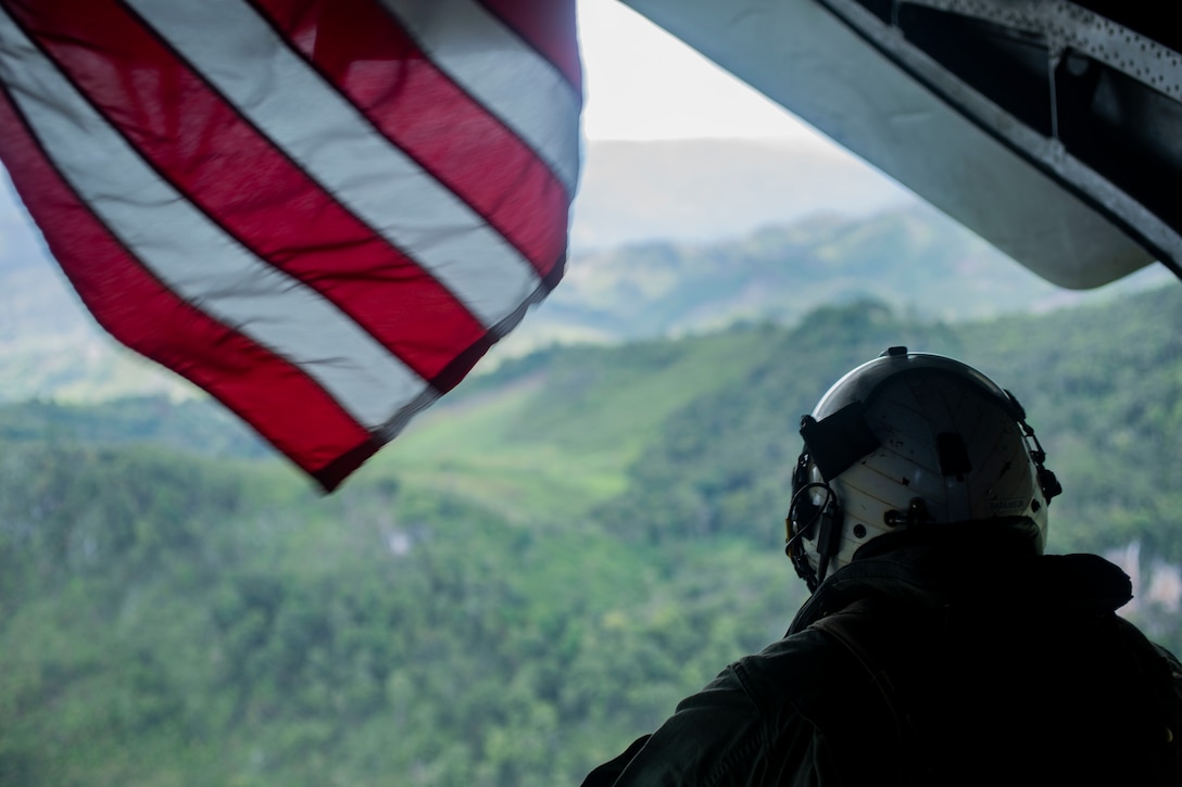 A Marine looks out the back of a helicopter