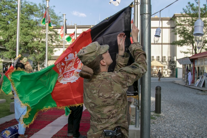 A service member raises the Afghanistan flag.