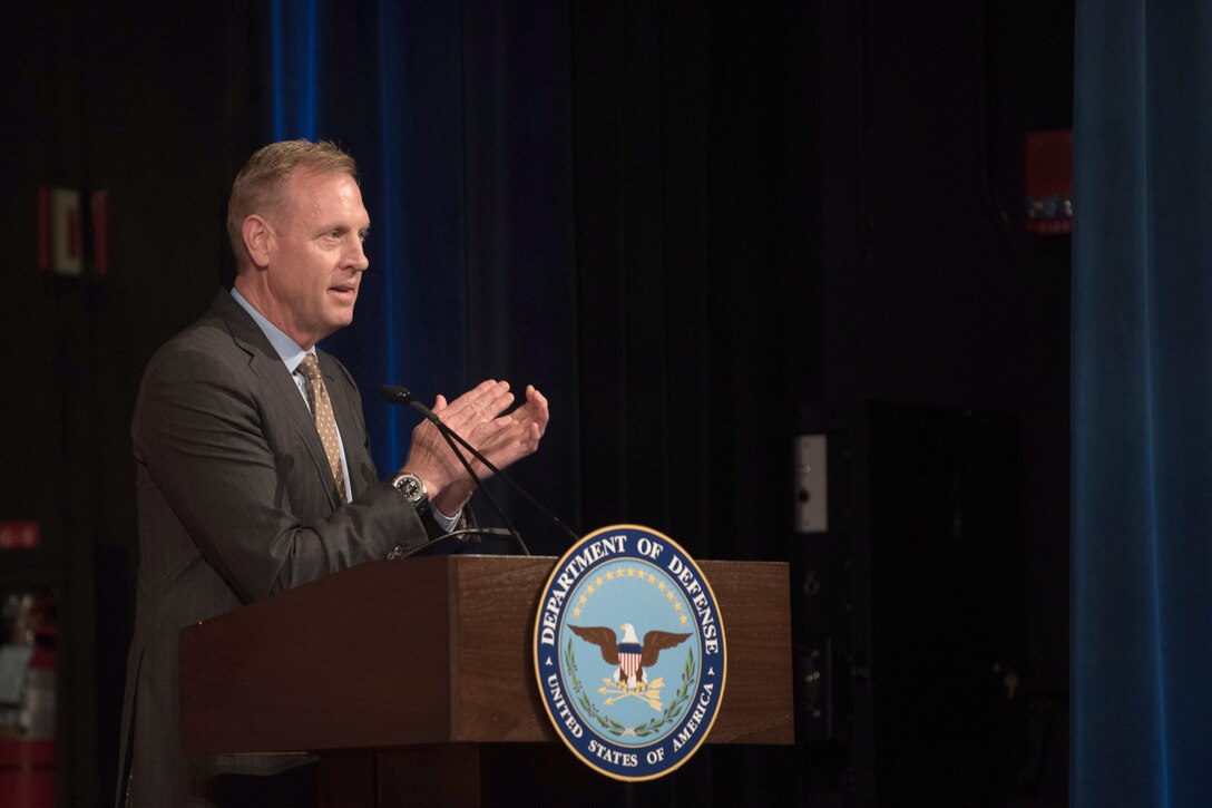 Deputy Defense Secretary Patrick M. Shanahan claps while standing at a lectern.