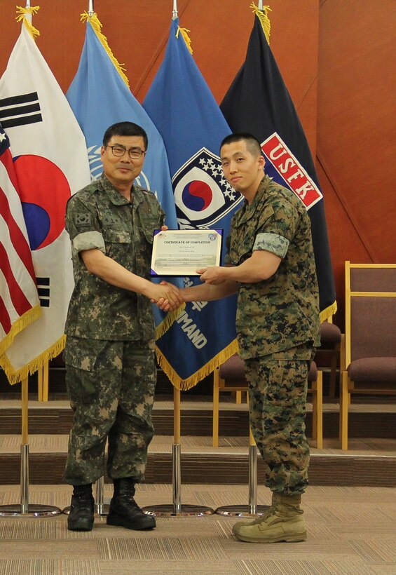USAG CAMP HUMPHREYS, Korea – Command Sgt. Maj. Joo Sik Kim, Combined Forces Command, Ground Component Command sergeant major (left), presents a certificate of completion to 1st Lt. Seakun Oh, U.S. Marine Corps Forces Korea, U.S.-Republic of Korea combined capability development officer, during the U.S. Forces Korea Security Cooperation Leader Development Program graduation ceremony here, June 8.  The program fostered understanding of U.S.-ROK support for security cooperation, combined capability development, and development of partner capacity. (Official U.S. Marine Corps photo by Sgt. Nathaniel Hanscom/Released)