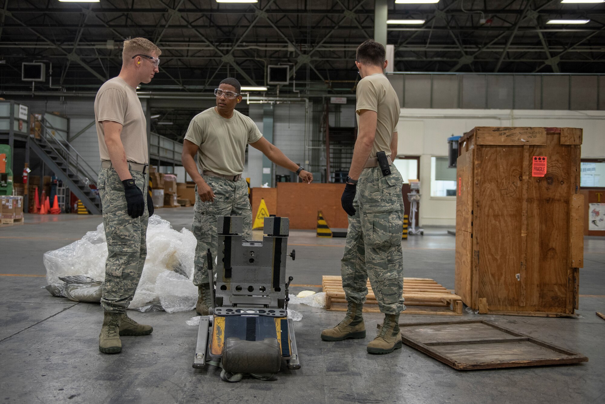 Tech. Sgt. Edwin Jacobo, center, 374th Logistics Readiness Squadron NCO in charge of outbound cargo, shows Staff Sgt. Charles Jaunich and Airman 1st Class Boaz Rogel, both 374th Secuirty Forces Squadron patrolmen, the item they would be shipping as part of the Wing Immersion Program at Yokota Air Base, Japan, June 20, 2018.