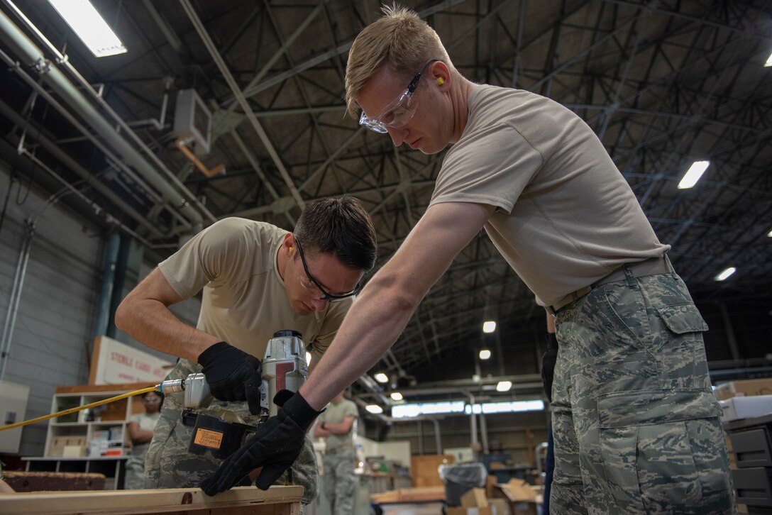 Airman 1st Class Boaz Rogel, left,, 374th Security Forces Squadron patrolman, and Staff Sgt. Charles Jaunich, 374th SFS base defense operations center controller, work together to assemble a container for the 374th Logistics Readiness Squadron as part of the Wing Immersion Program at Yokota Air Base, Japan, June 20, 2018.
