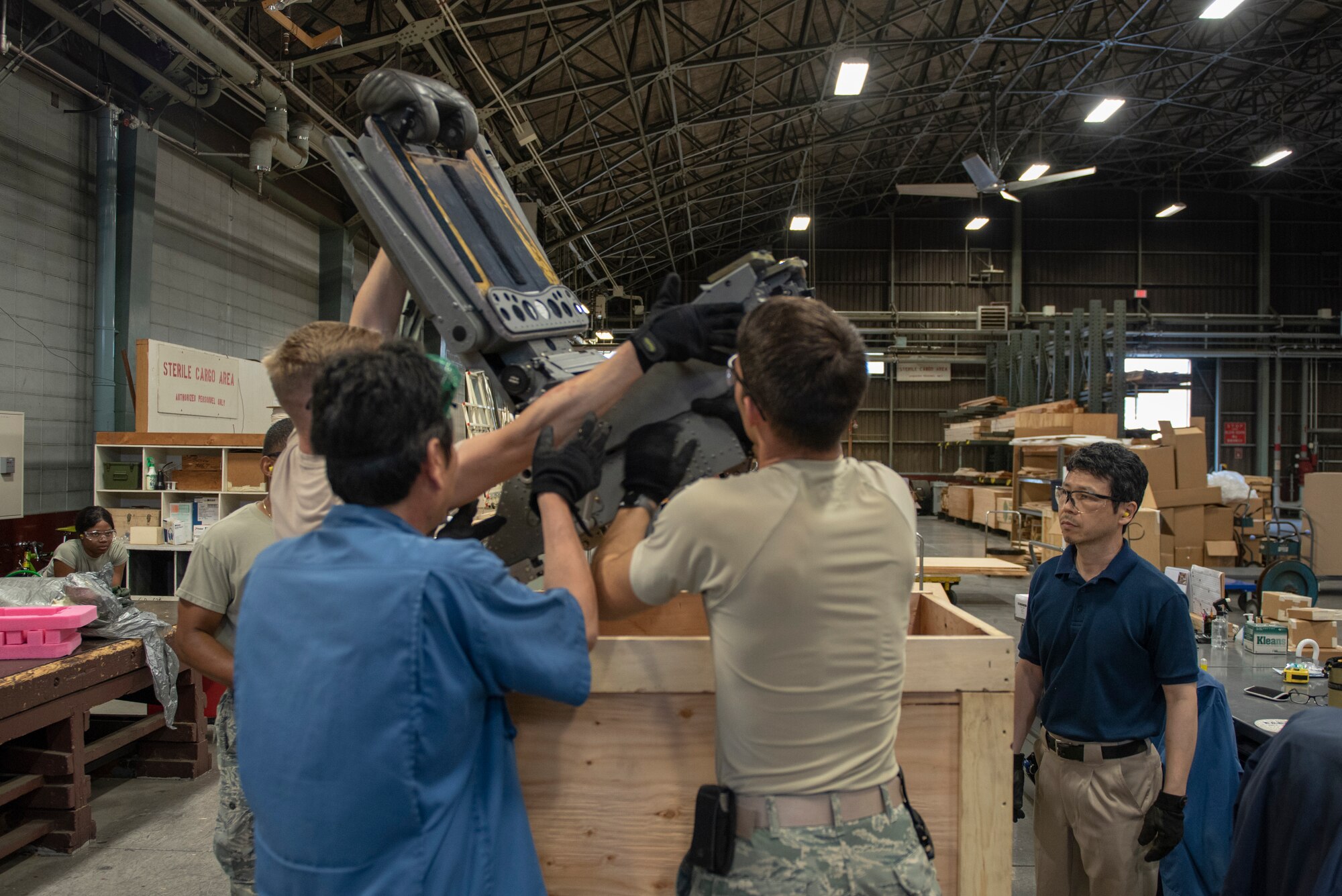 Members of the 374th Logistics Readiness Squadron and 374th Security Forces Squadron work together to load a seat into a packing container for shipment during the Wing Immersion Program at Yokota Air Base, Japan, June 20, 2018.