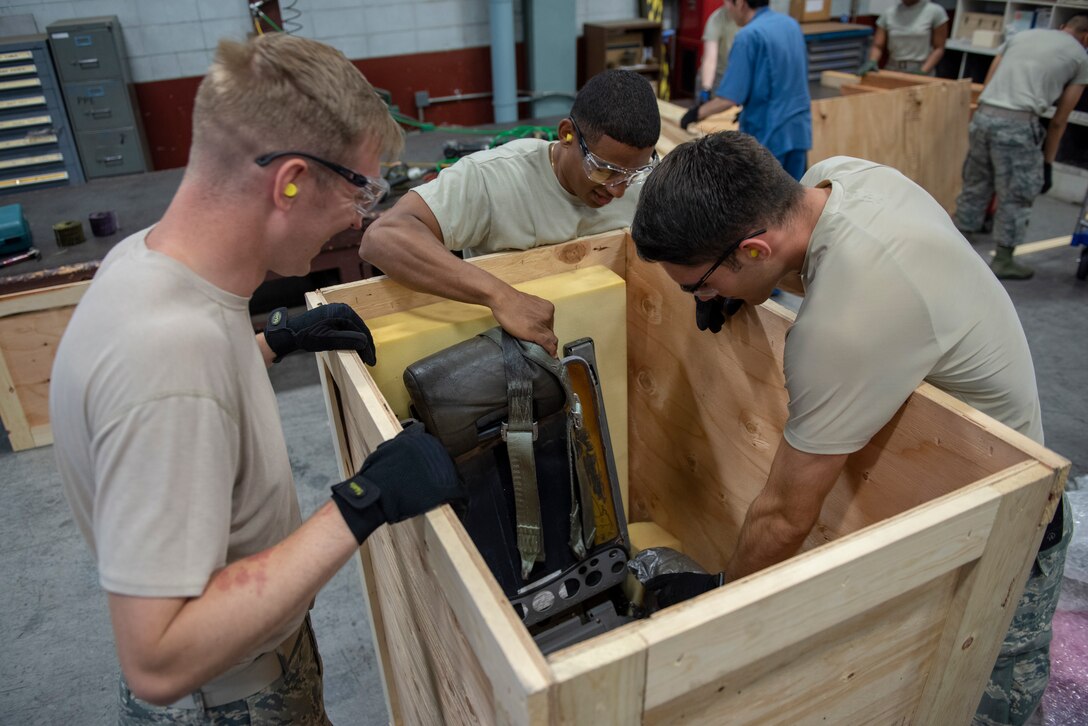 Staff Sgt. Charles Jaunich, left, 374th Security Forces Squadron base defense operations center controller, Tech. Sgt. Edwin Jacobo, center, 374th Logistics Readiness Squadron NCO in charge of outbound cargo, and Airman 1st Class Boaz Rogel, right, 374th SFS patrolman, work together to cushion cargo in its container before shipment during the Wing Immersion Program at Yokota Air Base, Japan, June 20, 2018.