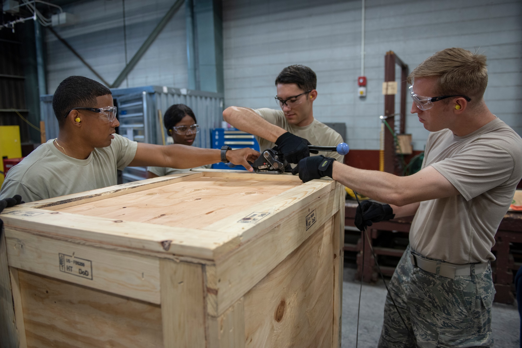 Tech. Sgt. Edwin Jacobo, left, 374th Logistics Readiness Squadron NCO in charge of outbound cargo, and Airman 1st Class Boaz Rogel, center, 374th Security Forces Squadron patrolman, and Staff Sgt. Charles Jaunich, right, 374th SFS base defense operations center controller, work together to secure the contents of a shipping container during a Wing Immersion program at Yokota Air Base, Japan, June 20, 2018.
