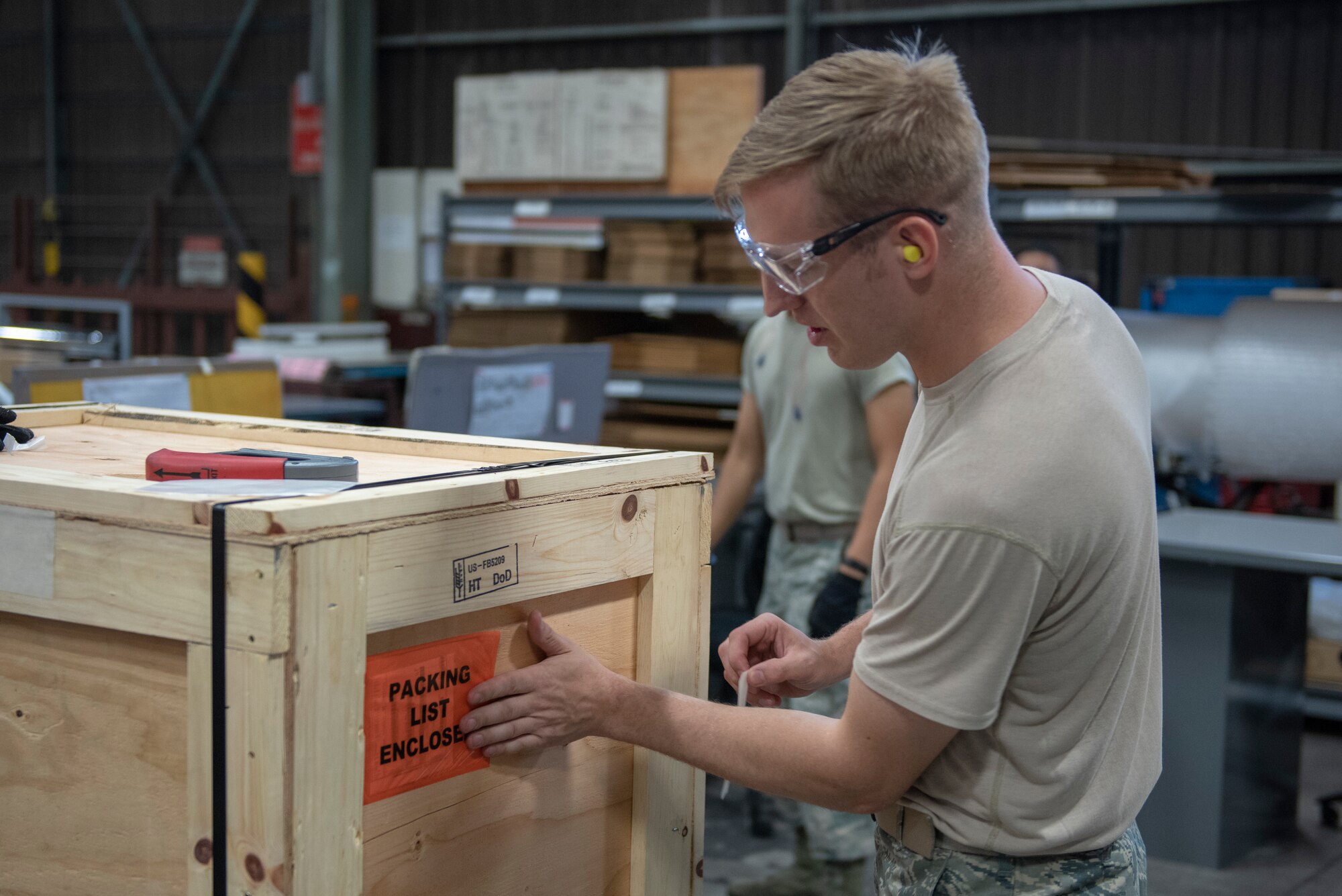 Staff Sgt. Charles Jaunich, left, 374th Security Forces Squadron base defense operations center controller, applies the shipping label to a container before shipment during a Wing Immersion program at Yokota Air Base, Japan, June 20, 2018.
