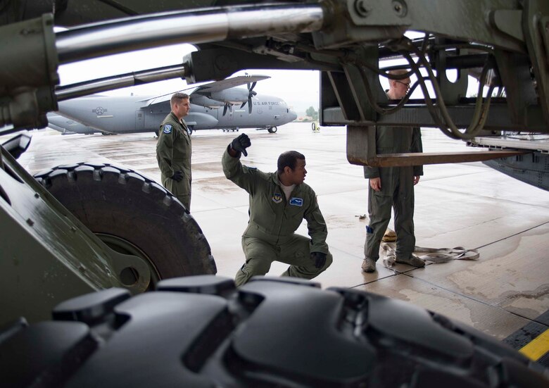 U.S. Air Force Airman 1st Class Jonathan Zapata, center, 37th Airlift Squadron C-130J Super Hercules aircraft loadmaster, directs a forklift operator loading cargo into a C-130J on Ramstein Air Base, Germany, June 12, 2018. Ramstein's loadmasters are skilled in loading and securing cargo such as vehicles and personnel inside a C-130J. (U.S. Air Force photo by Senior Airman Elizabeth Baker)