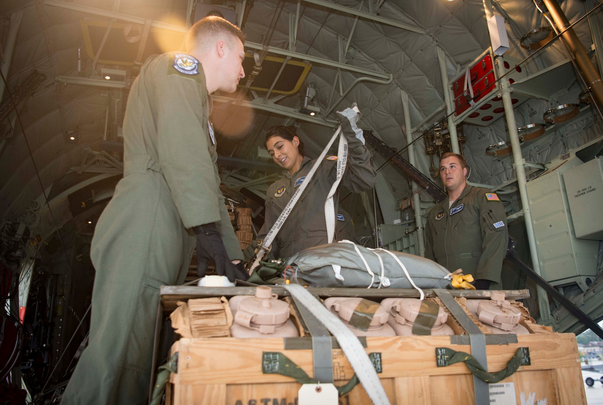 U.S. Air Force Staff Sgt. Johnathan Hasty, left, Senior Airman Vanessa Soriano-Cervantes, middle, and Staff Sgt. Matthew Fry, all 37th Airlift Squadron C-130J Super Hercules aircraft loadmasters, secure a low-cost, low-altitude bundle on a C-130J on Ramstein Air Base, Germany, June 12, 2018. After learning what kind of cargo they are loading, such as hazardous materials, palletized cargo or passengers, Ramstein's loadmasters configure the correct placement and space to balance the aircraft, making them an essential part of Ramstein's airlift mission. (U.S. Air Force photo by Senior Airman Elizabeth Baker)