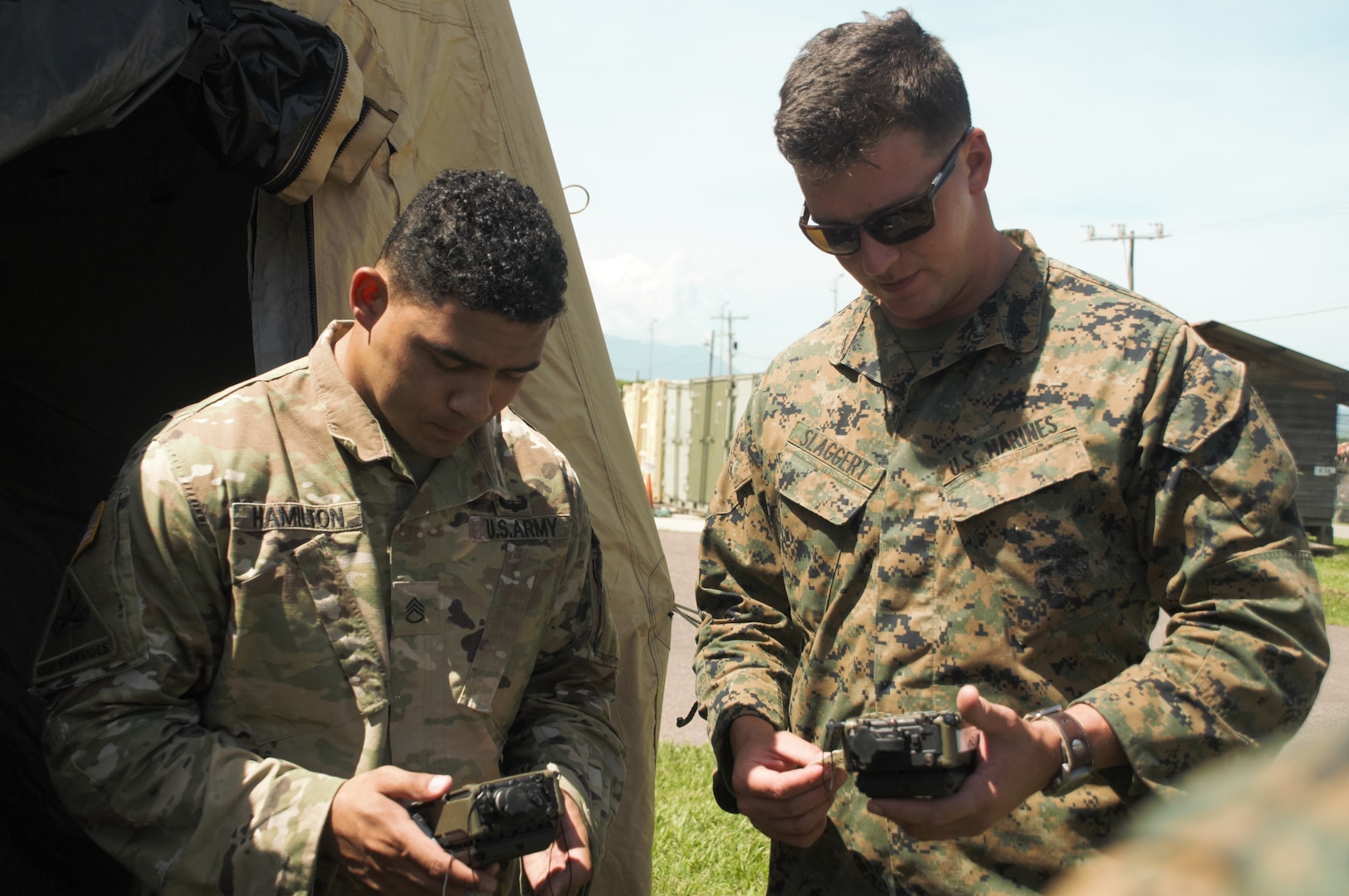 U.S. Army Staff Sgt.Tyrone Hamilton, left, the forward support noncommissioned officer in charge with Joint Task Force - Bravo's 1st Battalion, 228th Aviation Regiment, and U.S. Marine Cpl. Tyler Slaggert, a field radio operator with Special Purpose Marine Air-Ground Task Force - Southern Command, link their communications equipment together to secure reliable voice communication during a communications exercise aboard Soto Cano Air Base, Honduras, to prepare for future joint-level operations, June 19, 2018. The Marines and sailors of SPMAGTF-SC are conducting security cooperation training and engineering projects alongside partner nation military forces in Central and South America. The unit is also on standby to provide humanitarian assistance and disaster relief in the event of a hurricane or other emergency in the region.