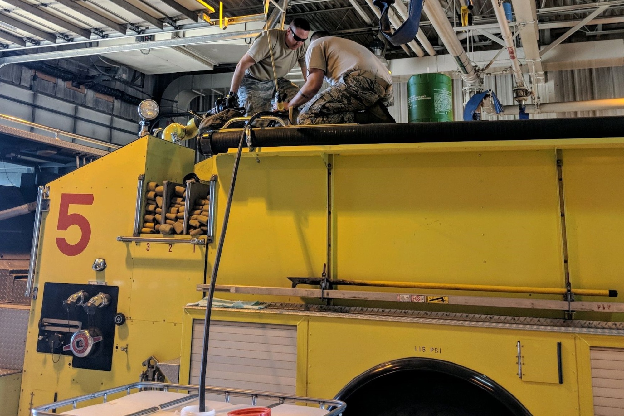Tech. Sgt. Brian Virden (left) and Master Sgt. Bryan Riddell, replace legacy firefighting foam at King Salmon Air Station, Alaska, with Phos-Chek 3 percent, a C6-based Aqueous Film Forming Foam, June 14.