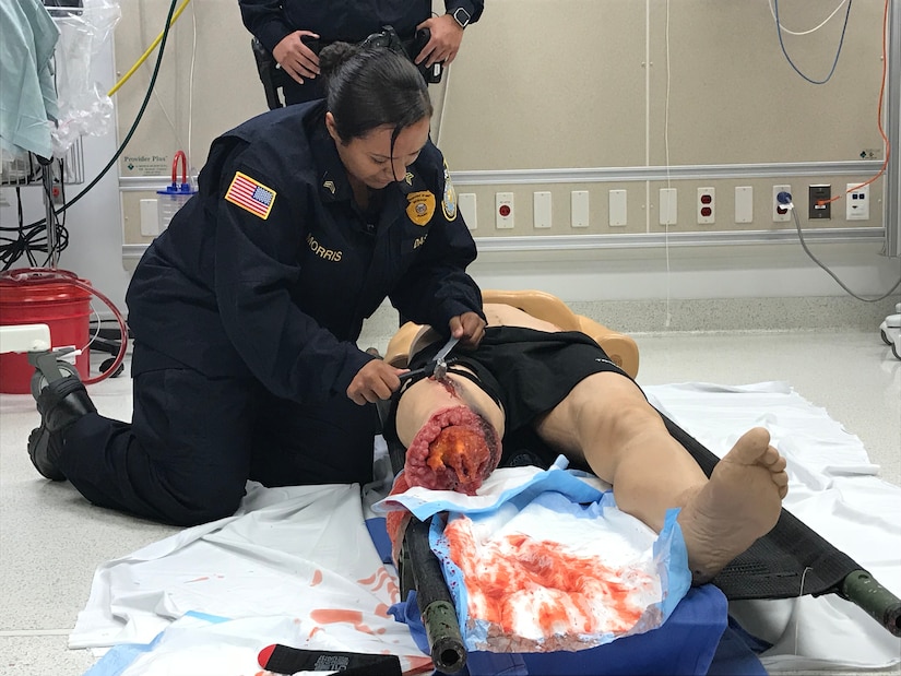 A security officer applies a tourniquet on a simulated casualty.