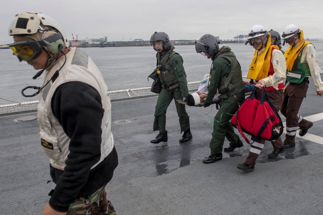Sailors transfer a mock patient during a medical training drill.