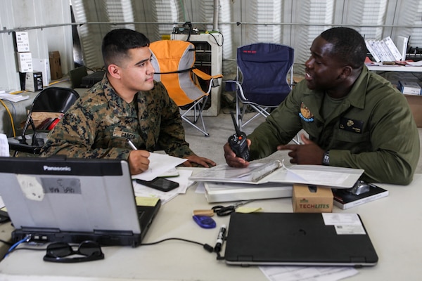 Sgt. Alan Garcia (left), an aviation supply specialist with Marine Light Attack Helicopter Squadron 775, Marine Aircraft Group 41, 4th Marine Aircraft Wing, discusses supply details with Staff Sgt. Tola S. Suleman (right), during Integrated Training Exercise 4-18 at Marine Corps Air Ground Combat Center Twentynine Palms, California. ITX 4-18 is a live-fire and maneuver combined arms exercise designed to train battalion and squadron-sized units in tactics, techniques, and procedures required to provide a sustainable and ready operational reserve for employment across the full spectrum of crisis and global engagement. (U.S. Marine Corps photo by Cpl Alexis B. Rocha/released)
