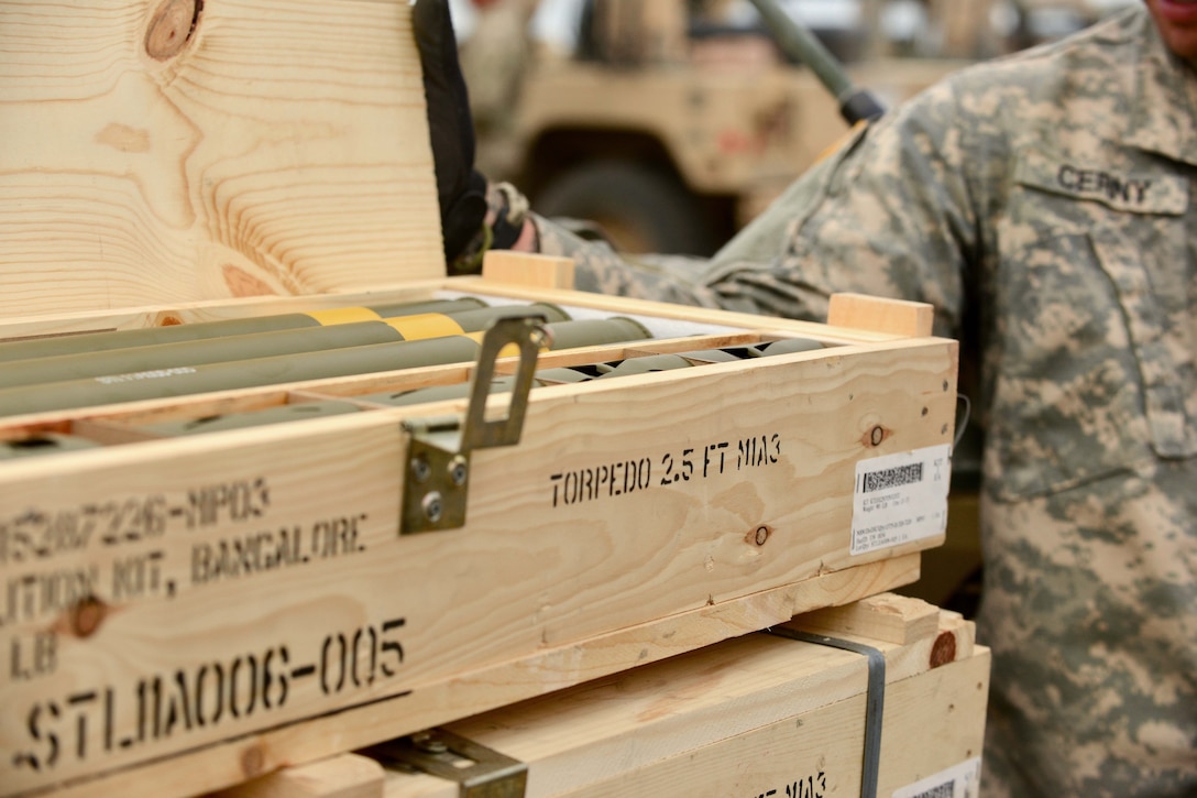 Soldiers open up and prepare a crate of M1A3 Bangalore torpedoes.
