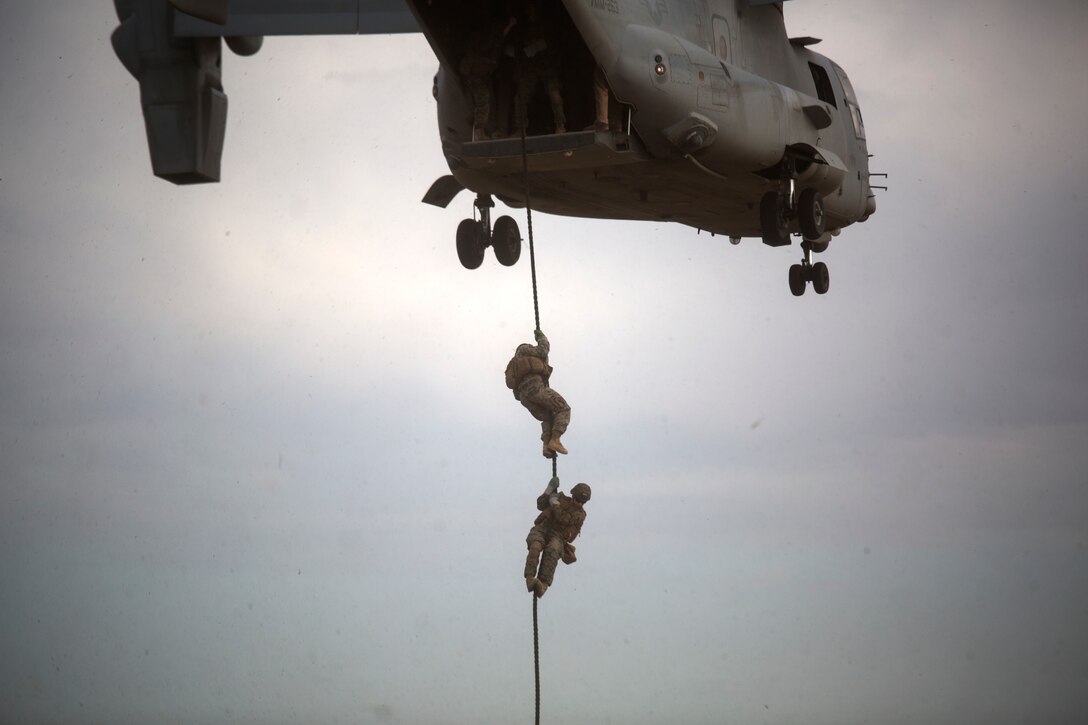Marines with Special Purpose Marine Air-Ground Task Force-Crisis Response Africa, Ground Combat Element 18.2, slide out of an MV-22B Osprey during a fast-rope training exercise at Naval Air Station Sigonella, Italy, June 13, 2018. The Marines of SPMAGTF-CR-AF practiced their fast-roping skills along with support from Marine Medium Tiltrotor Squadron 263. The fast rope training consisted of day and night operations to better prepare the Marines for crisis response.  (U.S. Marine Corps photo by Cpl. Taylor W. Cooper/Released)