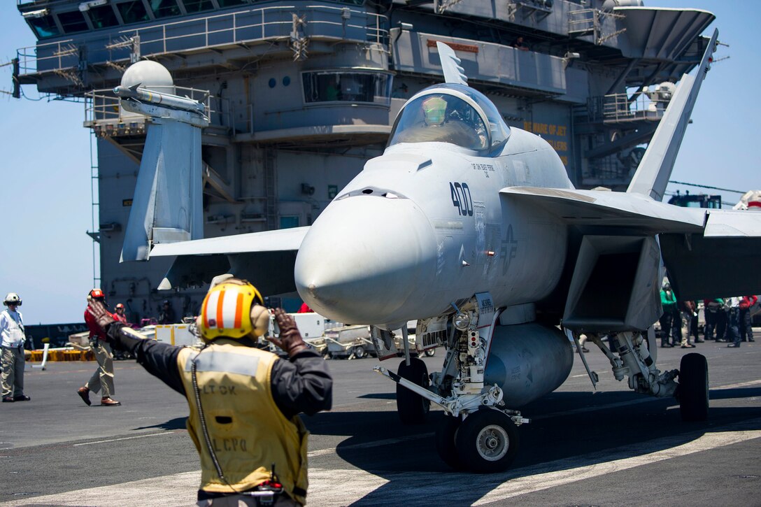A sailor directs an F/A-18E Super Hornet aircraft.