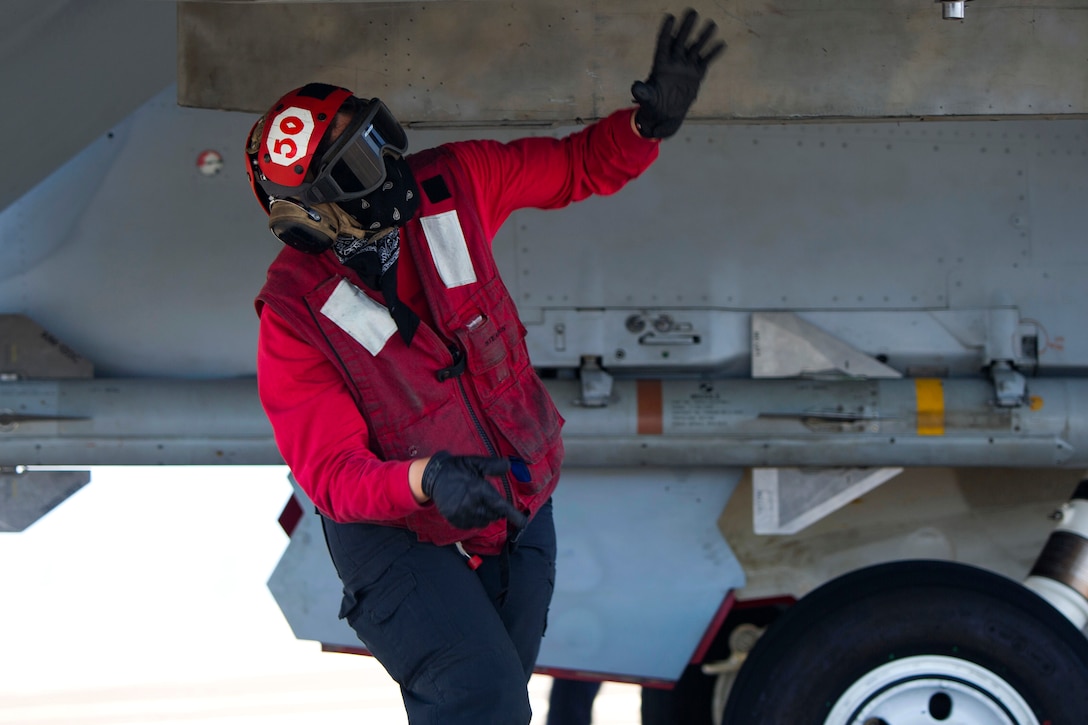 A sailor completes an ordnance check on an aircraft.