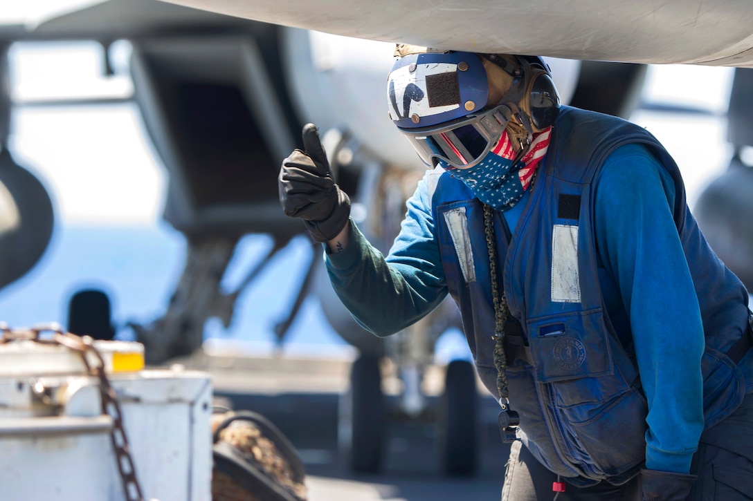 A sailor gives the thumbs-up after securing an F/A-18 Super Hornet aircraft.